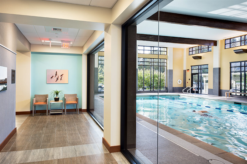 Fitness auditorium with glass walls looking into a swimming pool