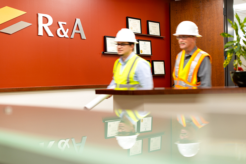 R&A employees leaving for a jobsite wearing hard hats and safety vests and carrying blueprints