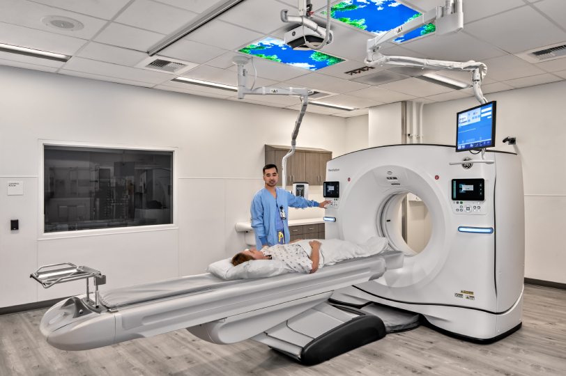 Medical technician positioning patient on CT scanner table in modern imaging suite
